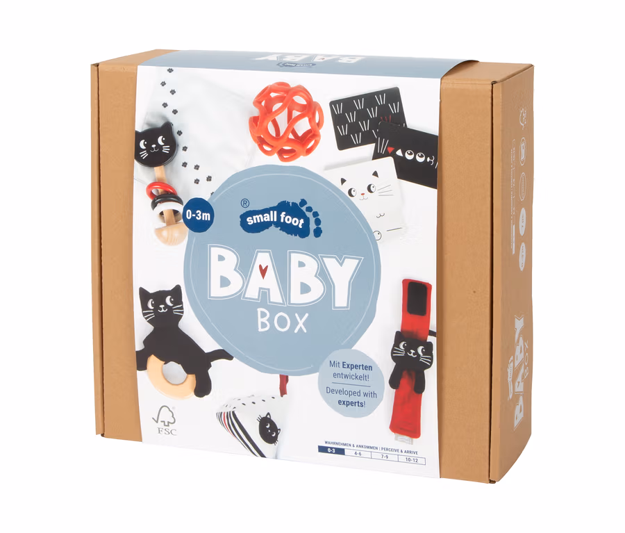 Brauner Karton der small foot Baby-Box, 0–3 Monate, mit Abbildungen von Babyspielzeug wie einem roten Greifling, schwarz-weißen Kontrastkarten und Katzen-Beißringen.