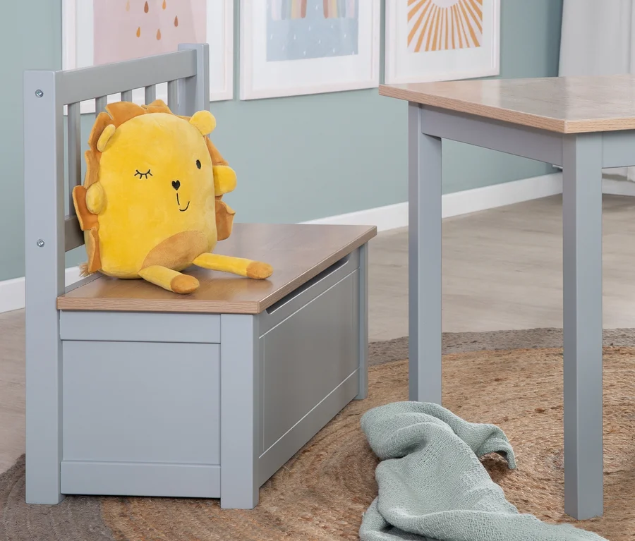 Gelbes Löwenkuscheltier sitzt auf roba Kindertruhenbank »Woody« neben Tisch auf Jute Teppich.