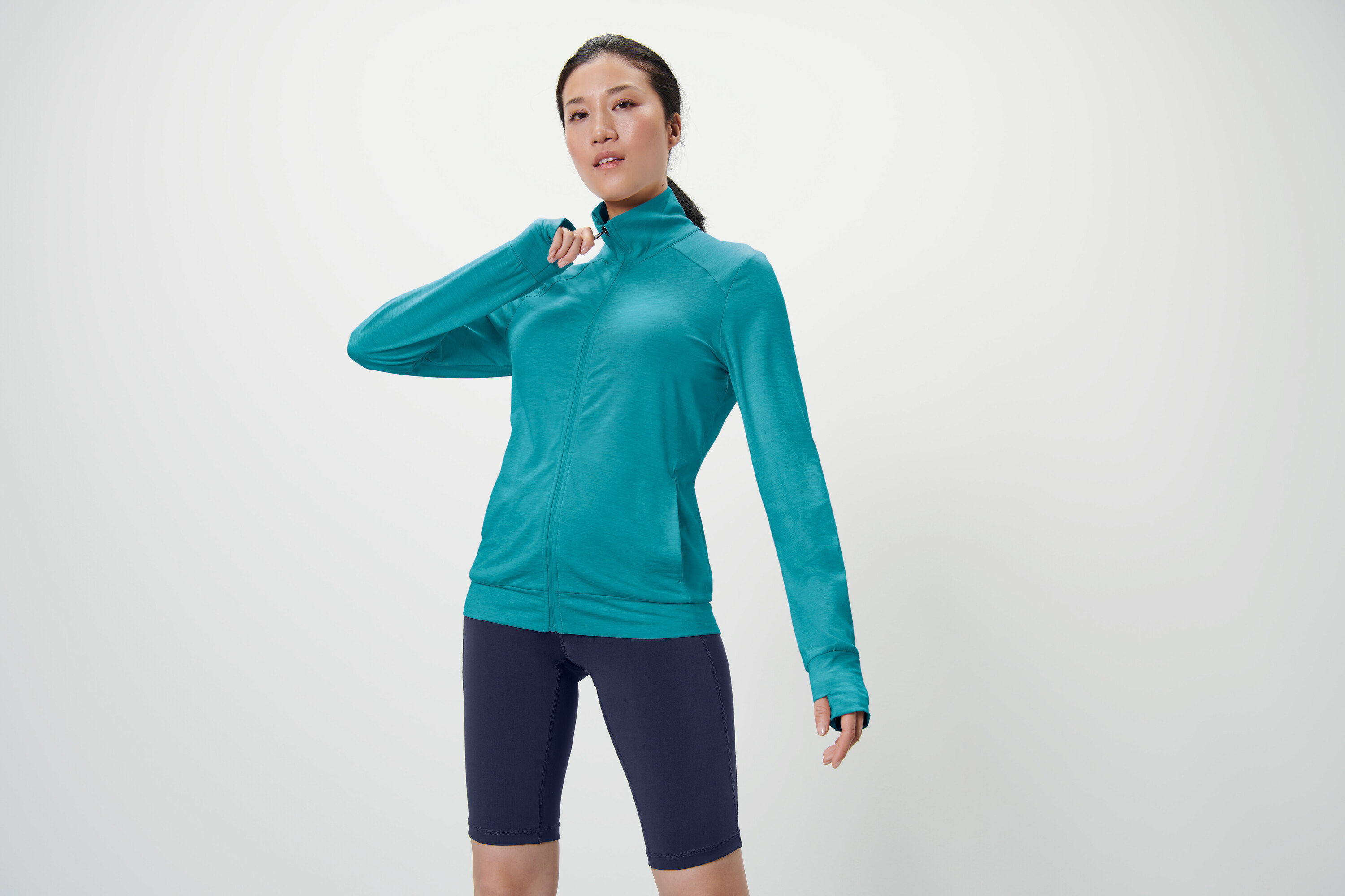 Frau posiert in türkiser Funktionsjacke.