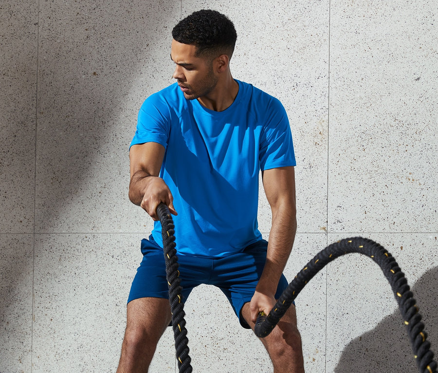 Mann trainiert mit Seilen in blauem Funktionsshirt.