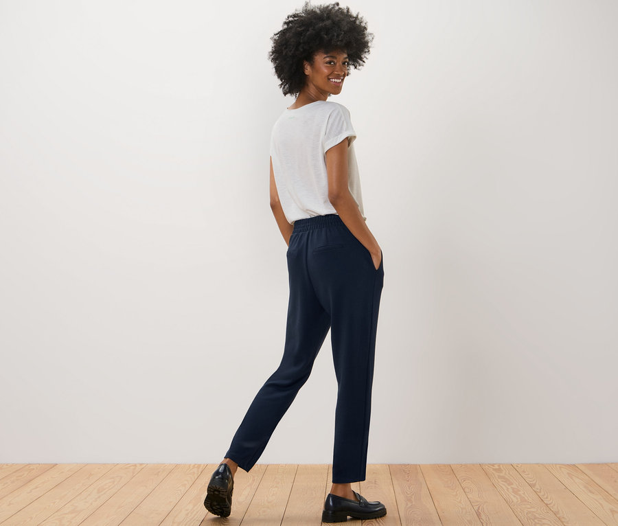 Frau posiert in marineblauer Joggpants und weißem T-Shirt.