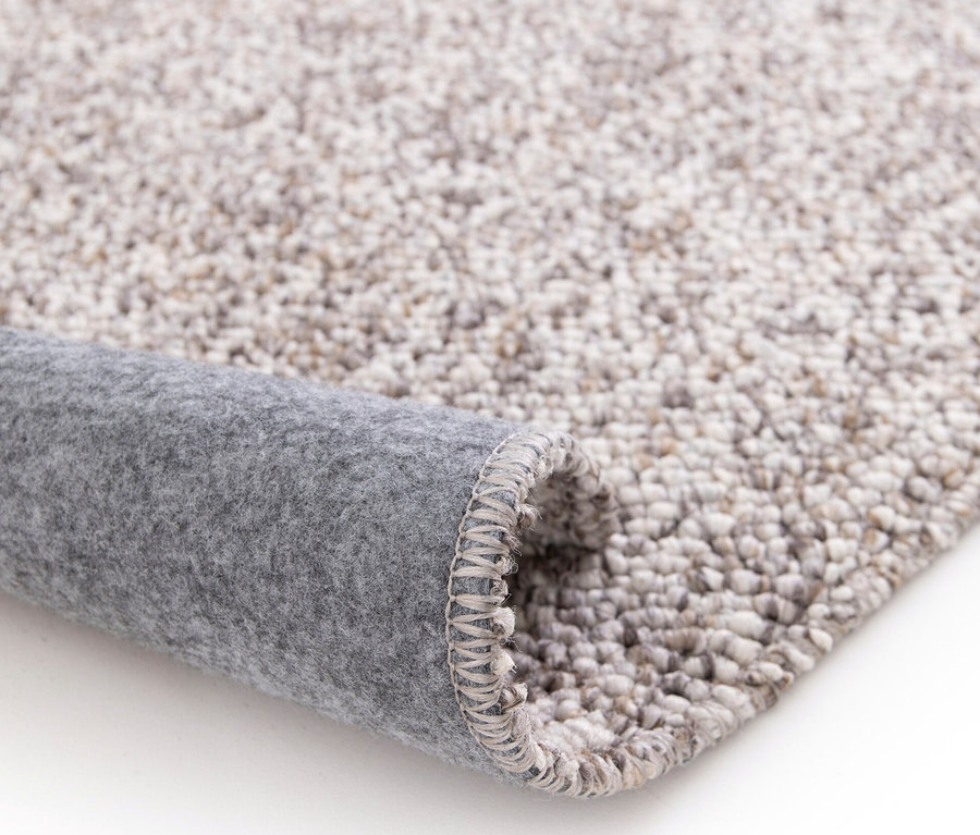 Detailansicht eines zusammengerollten, beigen Teppichs namens »Lino«.