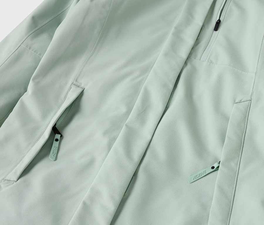 Detailaufnahme einer hellgrünen Jacke mit Reißverschlusstaschen.