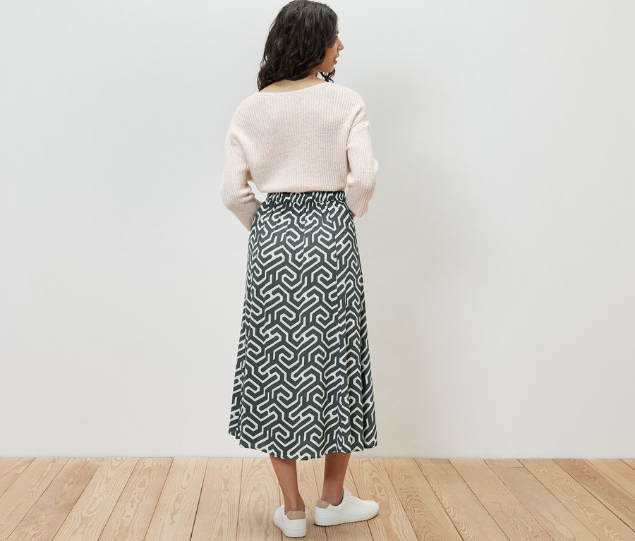 Frau von hinten in einem bedruckten Midi-Rock.