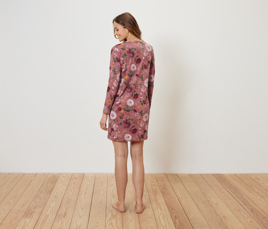 Frau steht mit dem Rücken zur Kamera und trägt ein geblümtes Kleid.