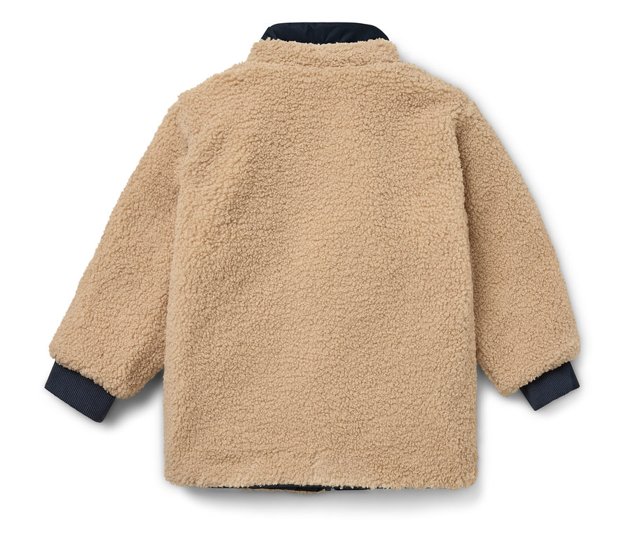 Eine beige Jacke mit dunkelblauen Bündchen und Kragen liegt auf einem weißen Hintergrund.