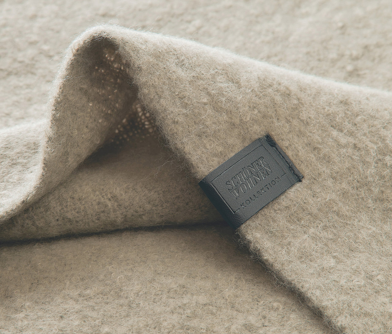 Detailaufnahme einer beigen Wolldecke mit schwarzem Etikett.