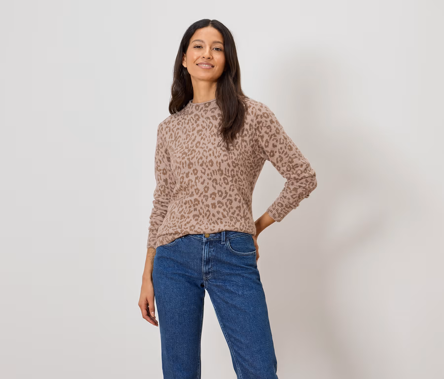 Frau trägt einen hellbraunen Pullover mit Leopardenmuster und blaue Jeans.