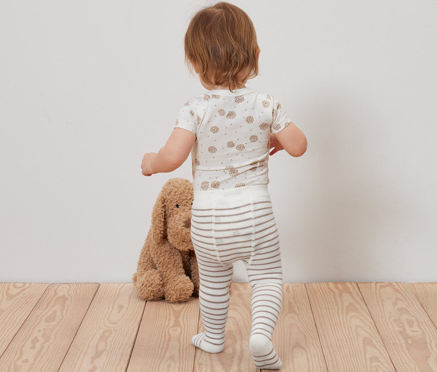 Baby steht mit dem Rücken zur Kamera und trägt eine 5 Paar Baby-Strumpfhose.