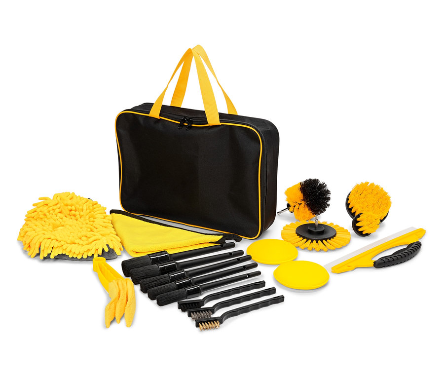Eine schwarze Tasche mit gelben Griffen und Bordüre, umgeben von gelben Waschhandschuhen, Tüchern, Bürsten und Schwämmen.