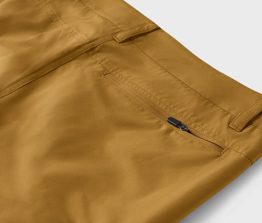 Detailaufnahme einer Khaki-Hose mit teilweise geöffnetem Reißverschluss an der Tasche.
