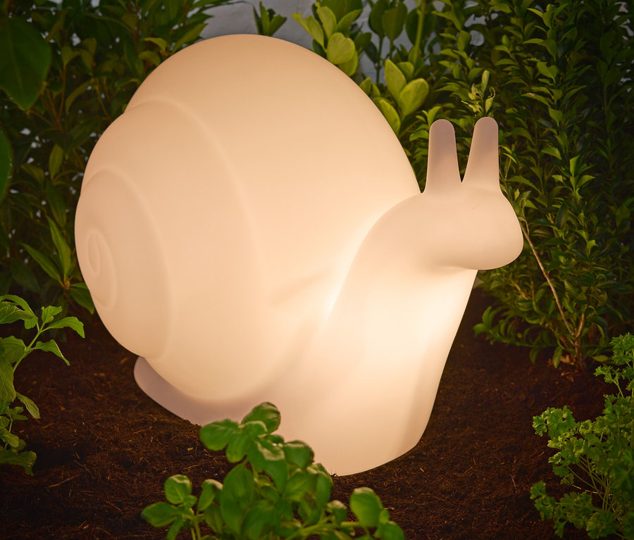Nahaufnahme einer Solar-Leuchte »Schnecke«, die auf dem Boden zwischen Pflanzen steht.