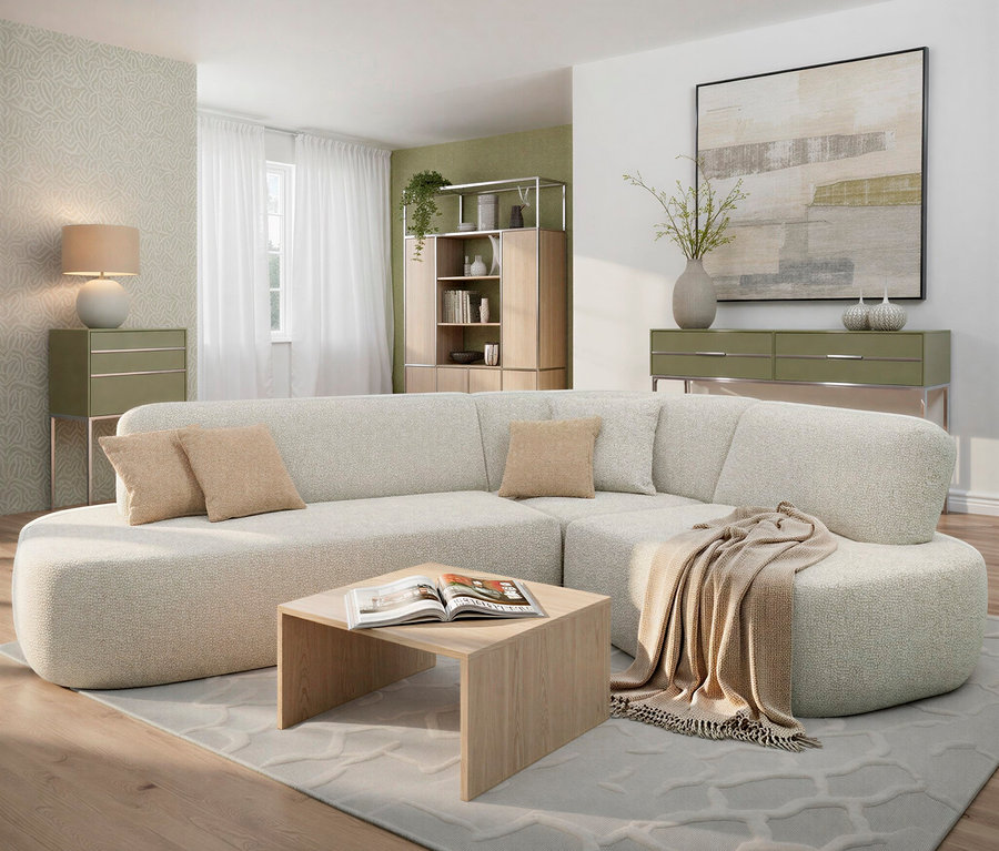 Wohnzimmer mit cremefarbenem Ecksofa, beigen Kissen und einem hellen Holztisch mit offenem Buch. Im Hintergrund Kommode, Regal und großes Bild.