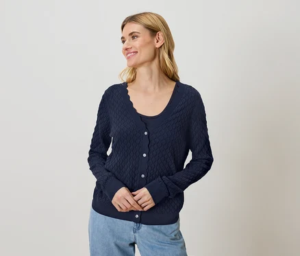 Frau trägt marineblaue Strickjacke und Jeans.