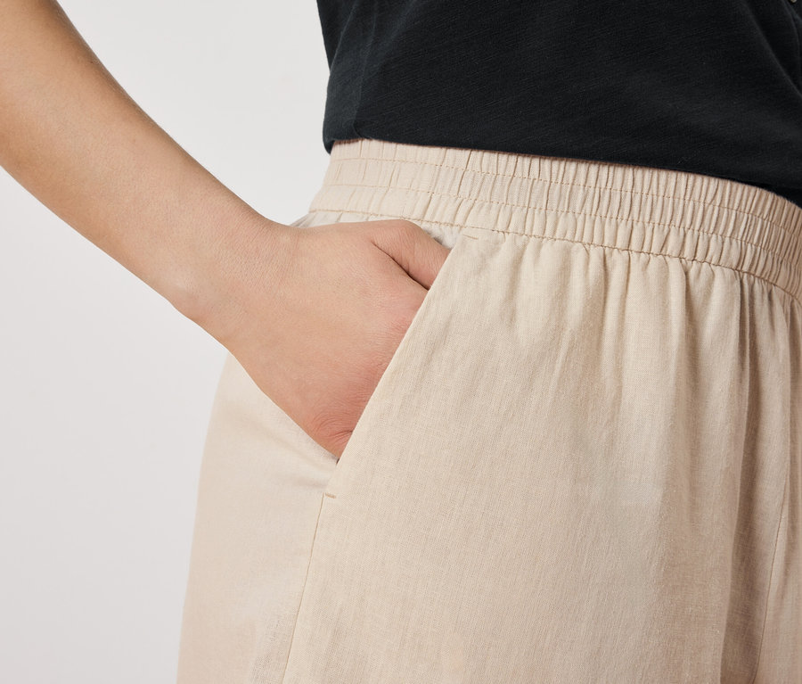 Frau mit Hand in der Tasche einer beigen Hose.