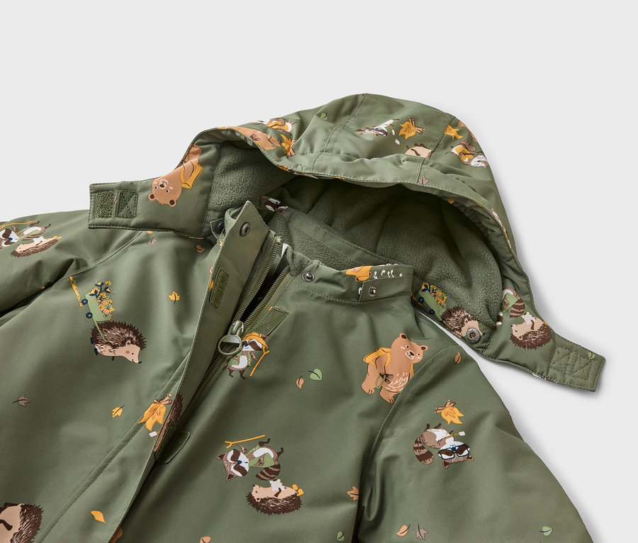 Nahaufnahme einer olivgrünen Jacke mit Kapuze, die mit Bären, Waschbären und Igeln bedruckt ist. Die Jacke ist teilweise geöffnet.