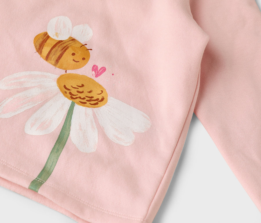 Auf einem rosa Stoff ist eine gemalte Biene auf einer Gänseblümchenblume.