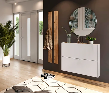 Flur mit weißer Schuhkommode unter rundem Spiegel, Holzgarderobe mit Jacke, Schachbrettmuster-Schuhe und Topfpflanze neben Tür.