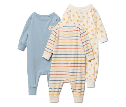 Drei Baby-Schlafanzüge liegen nebeneinander: einfarbig hellblau mit Wolkenapplikation, gestreift in Gelb-, Blau- und Orangetönen sowie weiß mit gelben Sonnen.