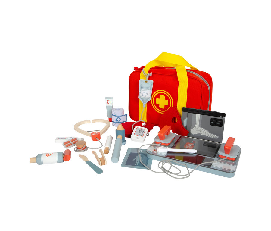 Rote small foot Notarzttasche mit gelbem Kreuz und Griffen, umgeben von Holzspielzeug-Medizinprodukten wie Stethoskop, Defibrillator und Röntgenbildern.