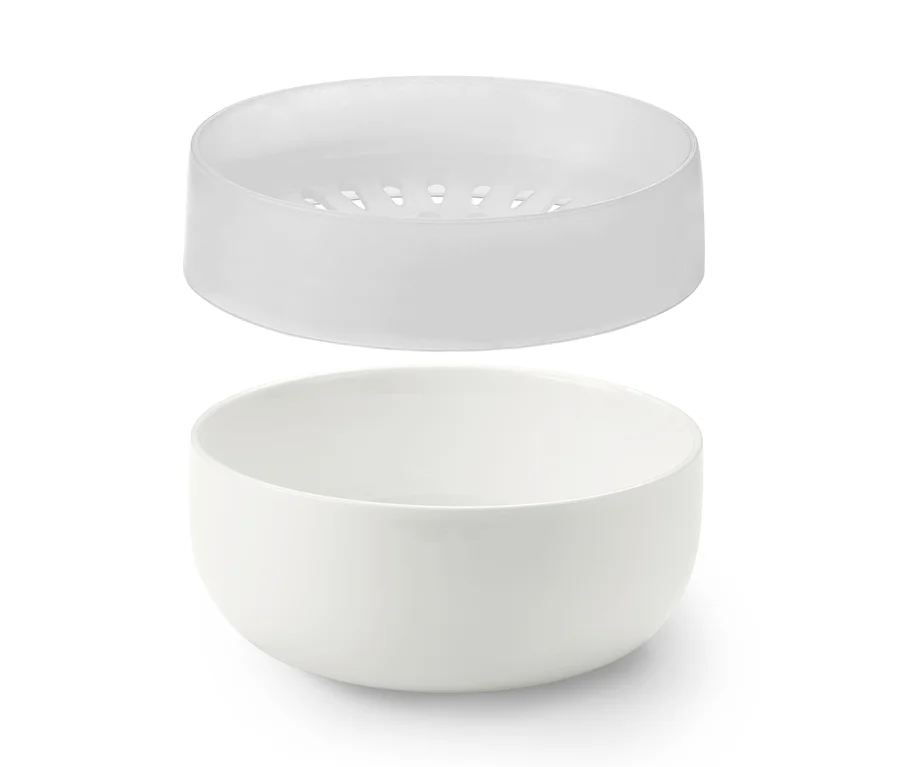 Eine weiße Mikrowellen-Porridge-Schale mit einem Sieb oben.