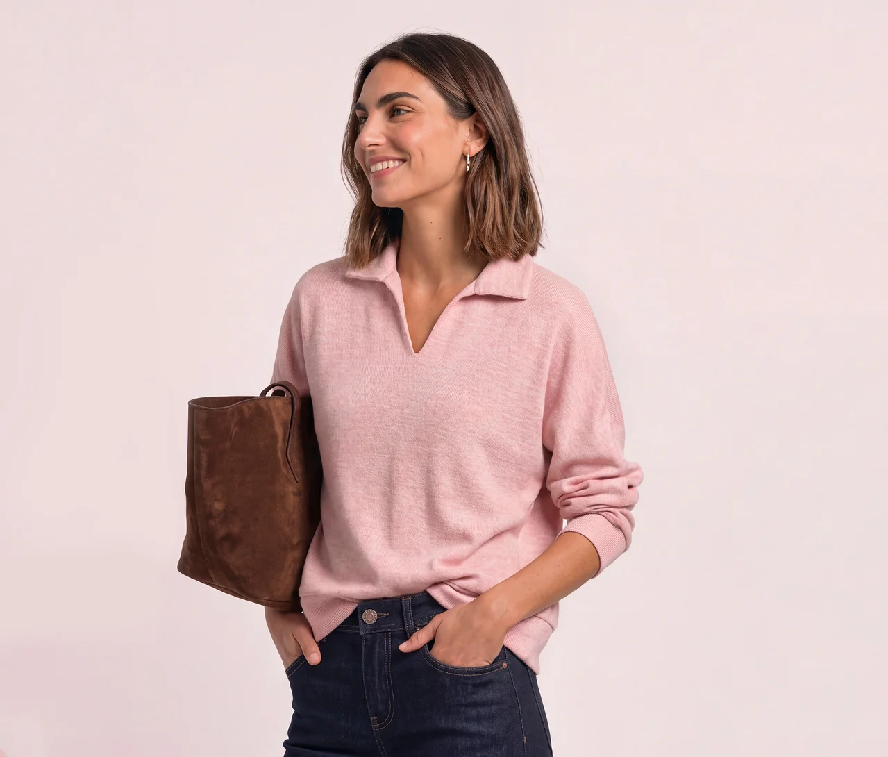 Lächelnde Frau mit kurzem Haar, die ein rosafarbenes Street One Poloshirt, dunkle Jeans und eine braune Tasche trägt.