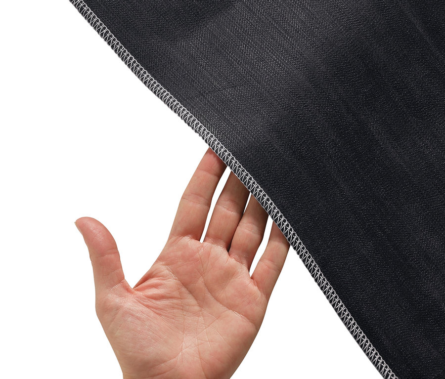 Hand hält Rand von schwarzem Stoff mit weißem Overlock-Stich.
