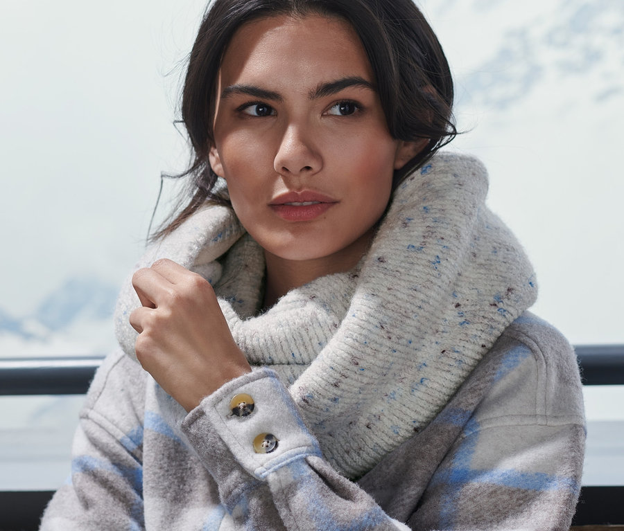 Frau sitzt draußen und trägt einen Strick-Schlauchschal.