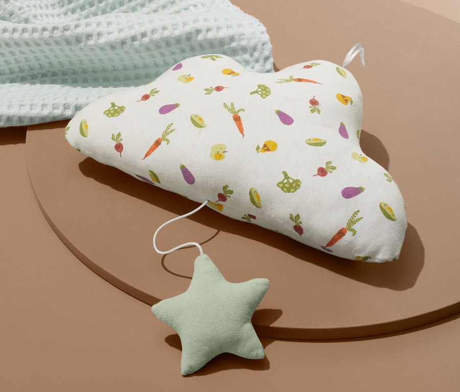 Eine Baby-Spieluhr »Wölkchen« mit Gemüse-Motiv liegt auf einer braunen Unterlage neben einer hellblauen Decke.