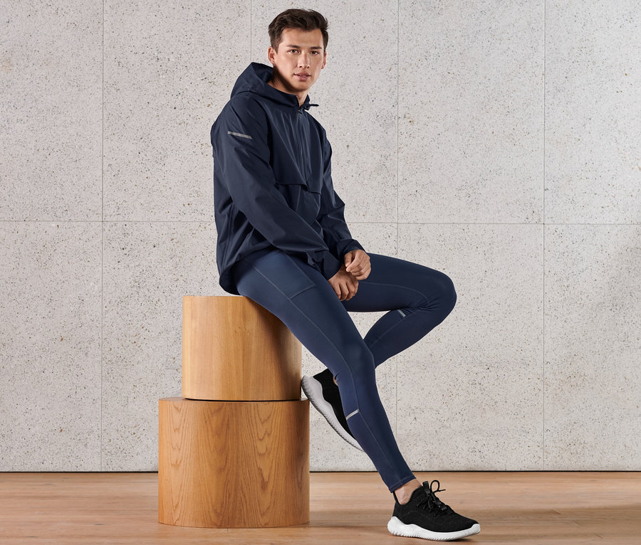 Mann sitzt auf Holzwürfeln und trägt eine blaue Performance-Lauftight.