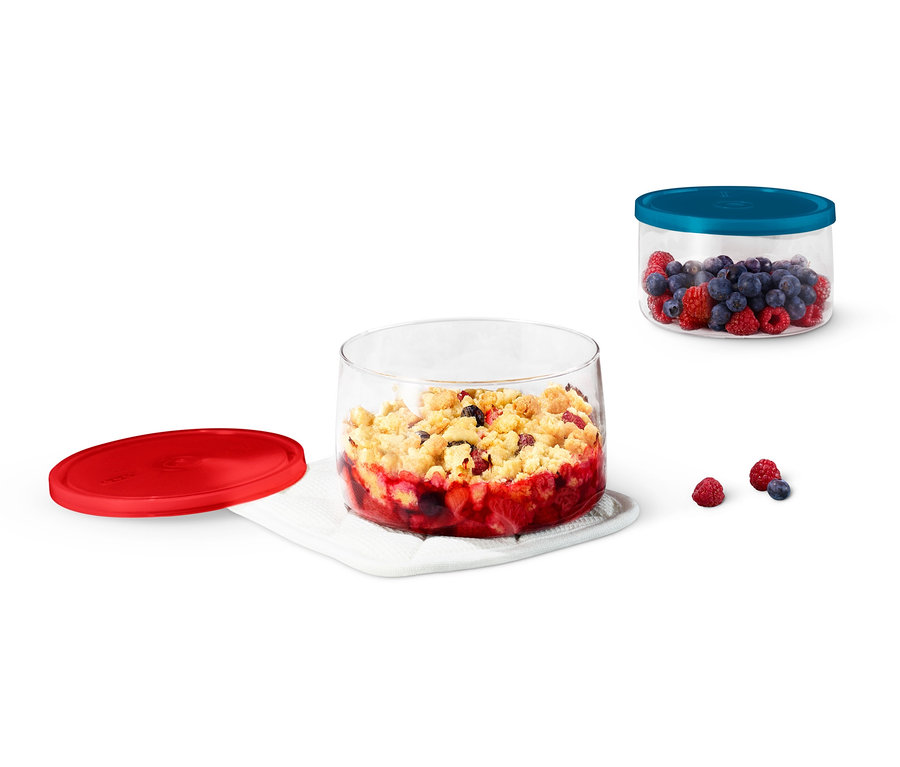 Zwei Glas-Auflaufformen, eine mit Obstkuchen und die andere mit Blaubeeren und Himbeeren.