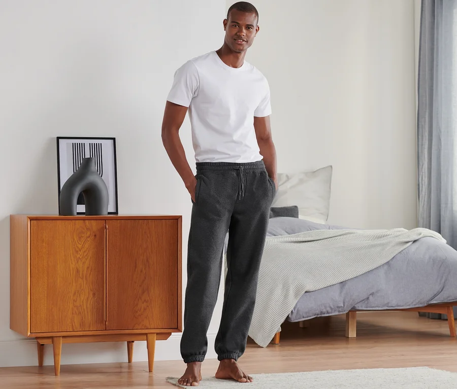Mann steht im Schlafzimmer und trägt eine Sweathose.