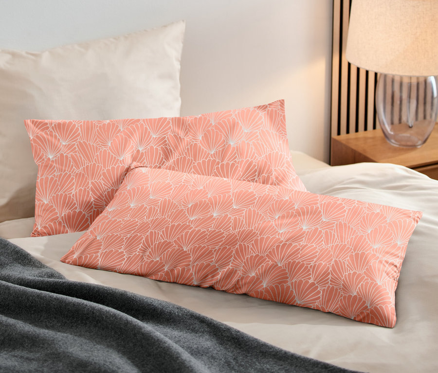 Zwei koralle Microfaser-Kopfkissenbezüge (ca. 80 x 40 cm) liegen auf einem Bett neben einer grauen Decke.