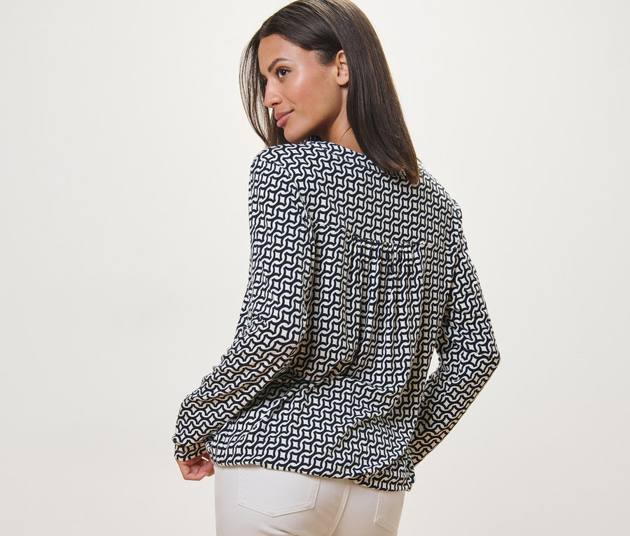 Frau blickt über die Schulter und trägt ein bedrucktes Blusenshirt, navy.