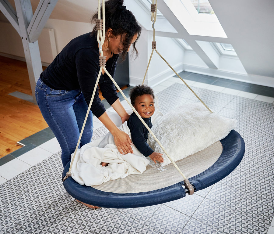 Frau legt eine Decke auf eine HUDORA Nestschaukel »Lounge«, midnight, Ø 110 cm, in der ein lächelnder Junge sitzt.