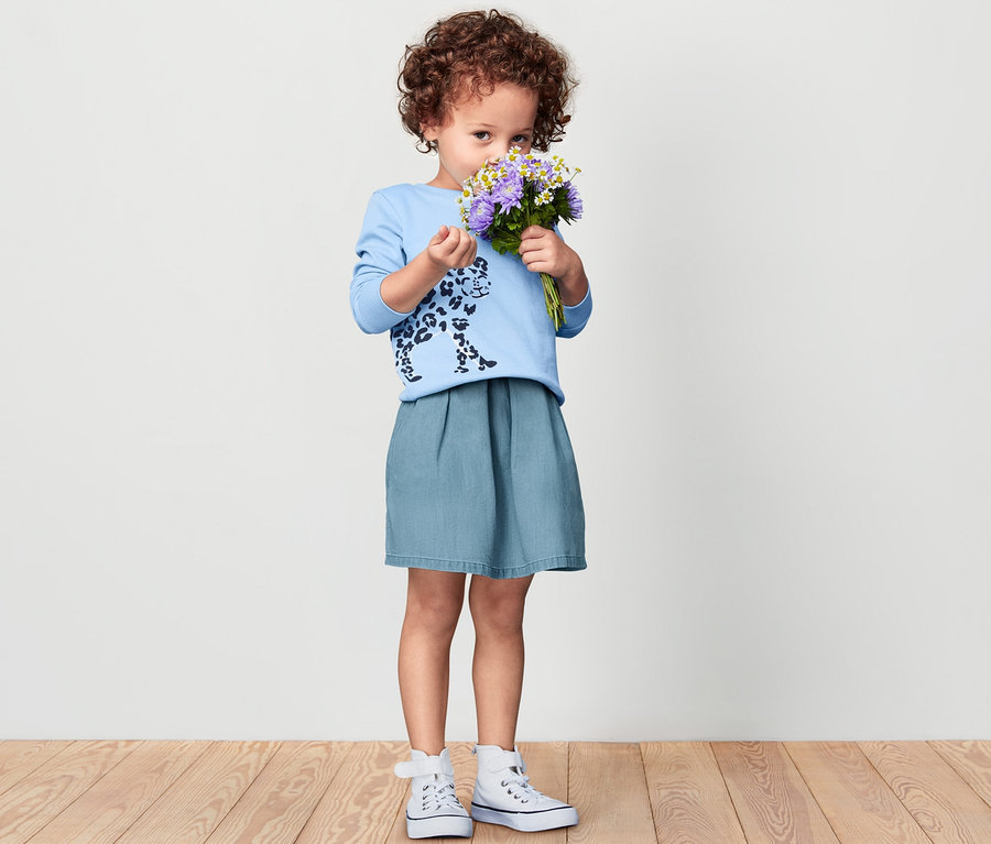 Mädchen hält Blumenstrauß und trägt einen Kinder-Denim-Rock.