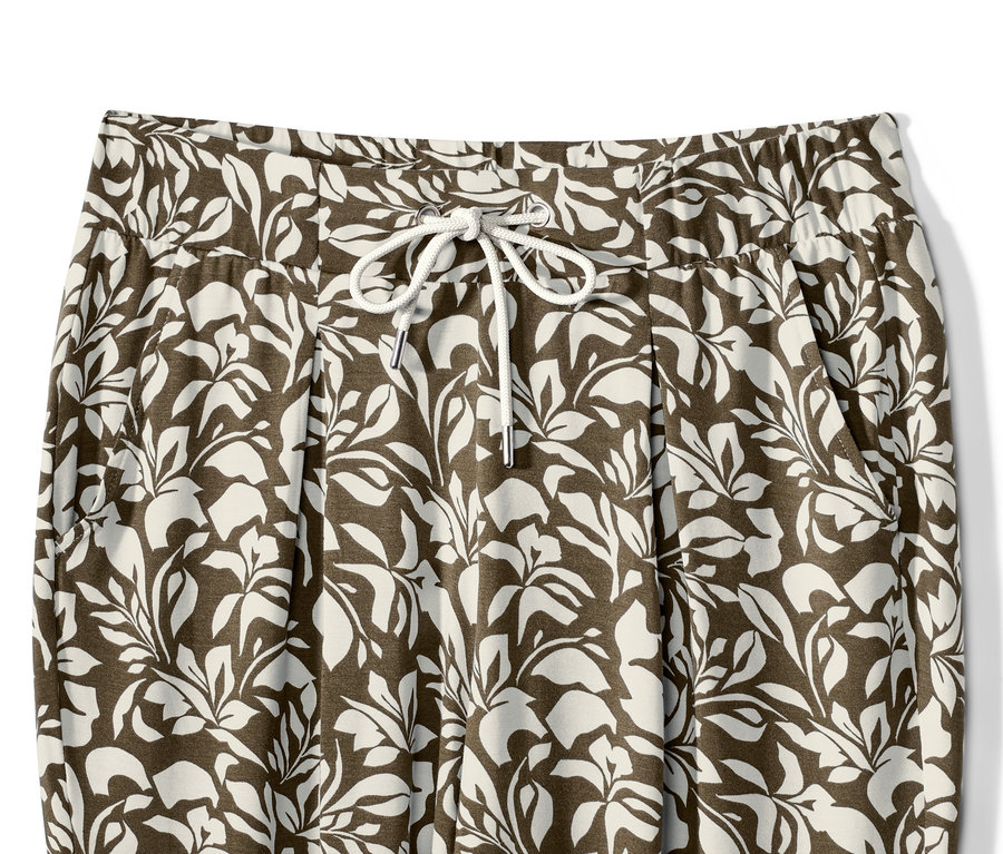 Detailaufnahme einer bedruckten Jerseyhose mit Blattmuster und Kordelzug in der Taille.