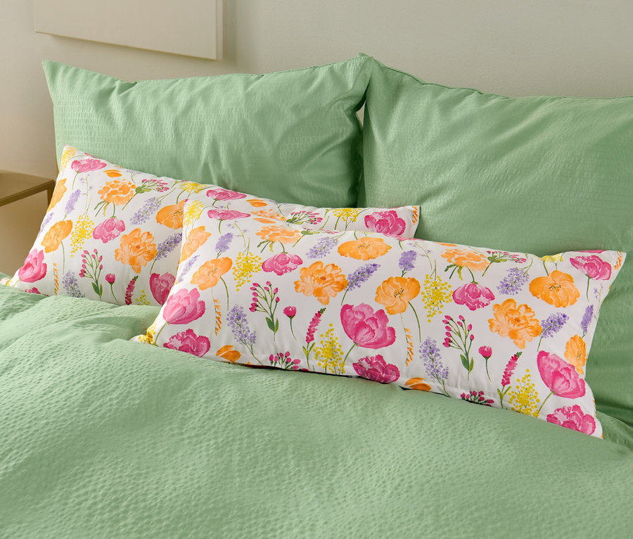 Auf einem Bett liegen zwei Microfaser-Kopfkissenbezüge mit Blumenmuster.