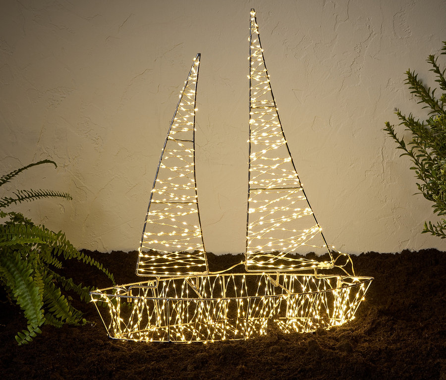 Ein beleuchtetes LED-3D-Outdoor-Boot steht neben Pflanzen auf dem Boden.