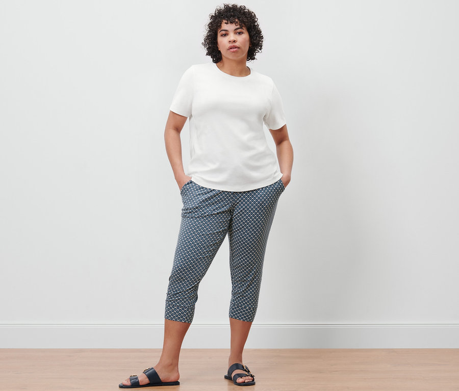 Frau posiert in einem cremefarbenen Basic T-Shirt und einer bedruckten 3/4-Jerseyhose.