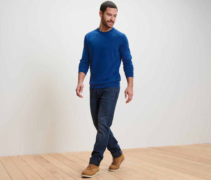 Mann geht und trägt einen blauen Merino-Pullover.