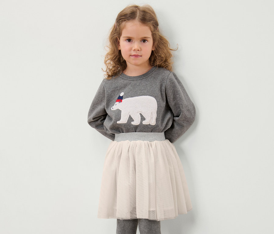 Mädchen posiert in grauem Sweatshirt mit Eisbär-Motiv und Kinder-Tüllrock.