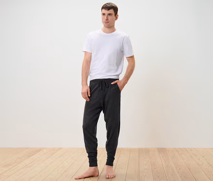 Mann steht in weißem T-Shirt und Feinstrick-Homewearhose.