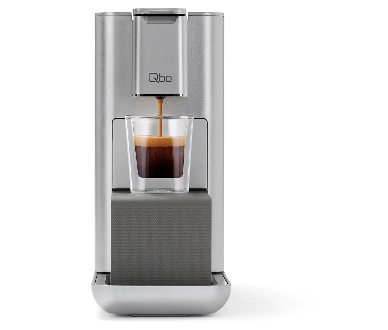 Kaffee fließt aus einer silbernen Qbo Kaffeemaschine in ein Glas.
