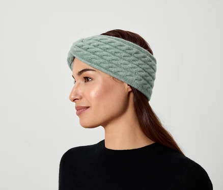 Porträt einer Frau mit braunen Haaren, die ein hellgrünes Strickstirnband trägt.