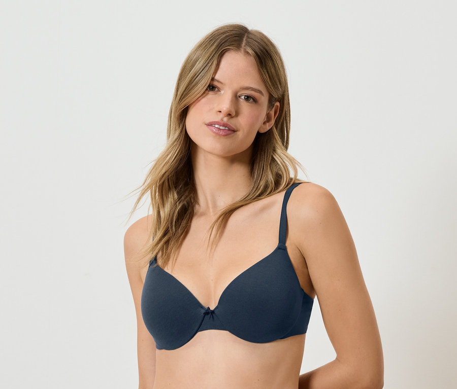 Frau mit braunen Haaren trägt einen marineblauen BH.