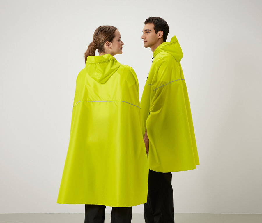 Zwei Personen stehen nebeneinander und tragen gelbe Regenponchos mit Kapuze.