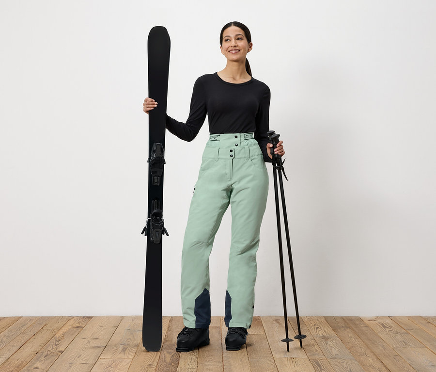 Frau hält Ski und Skistöcke.