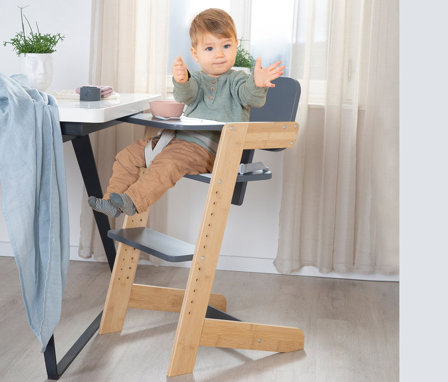 Kind sitzt im anthrazitfarbenen roba Babyhochstuhl am Tisch.