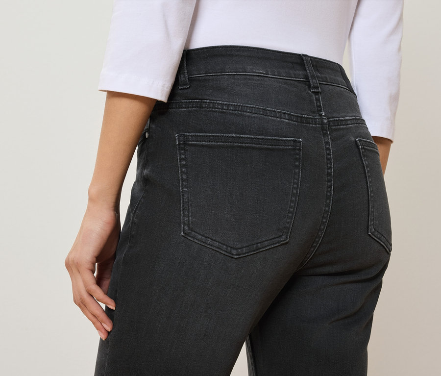 Rückansicht einer Frau in schwarzen Jeans und einem weißen T-Shirt.